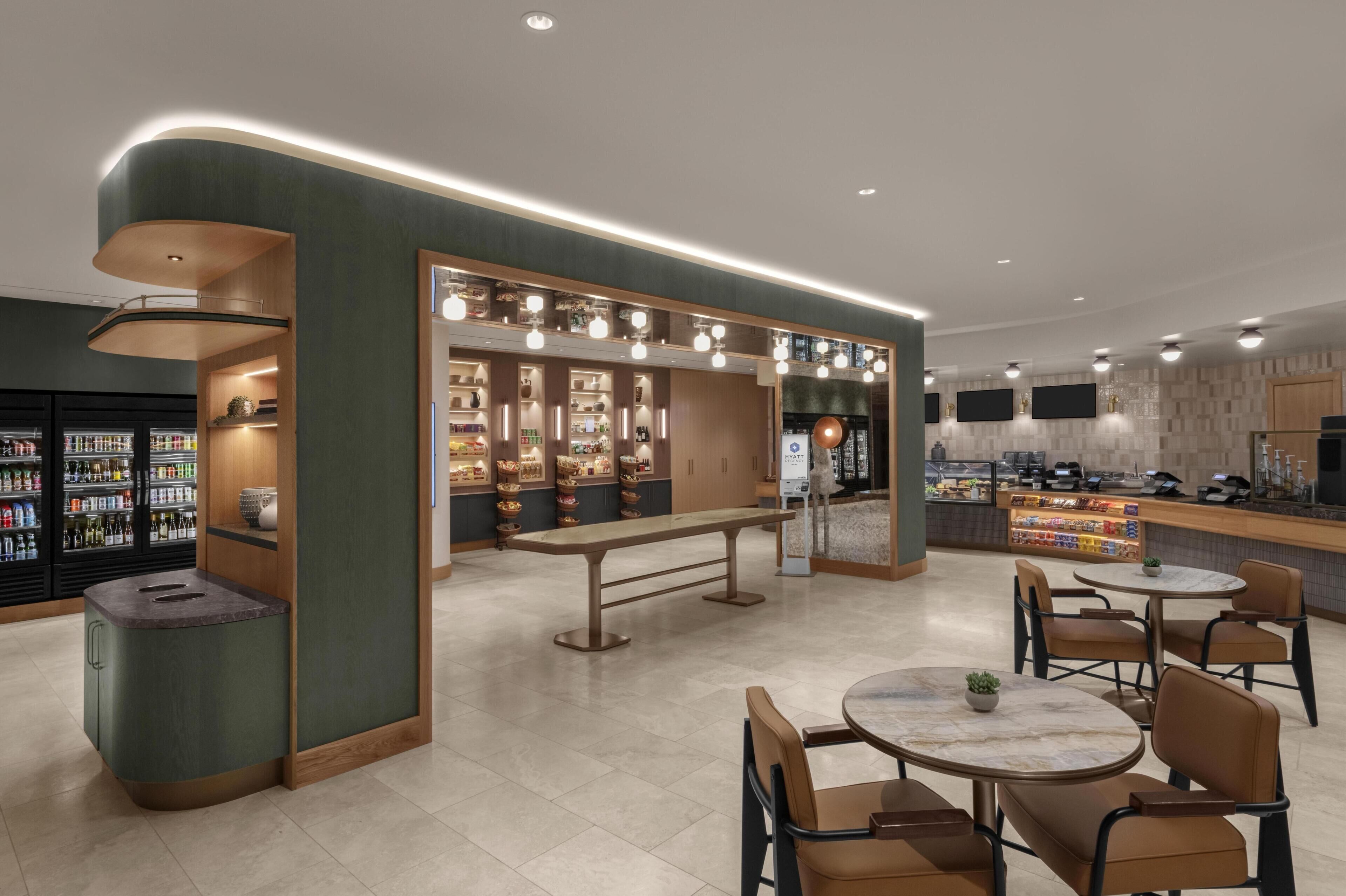 A modern cafe with a counter, seating area, and shelves with beverages.