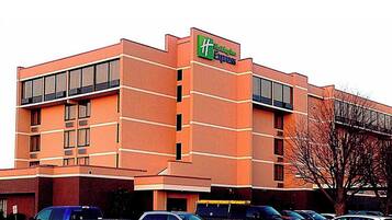 A Holiday Inn Express hotel with a brick facade, large windows, and a parking lot with several cars.