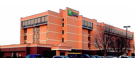 A Holiday Inn Express hotel with a brick facade, large windows, and a parking lot with several cars.