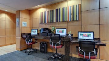 A reception area with a wooden panel wall, three computer workstations, and two office chairs.