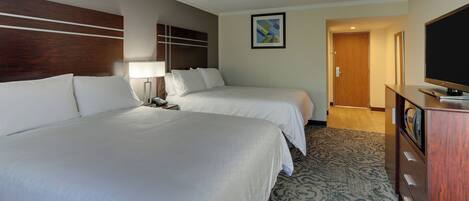 Habitación de hotel con dos camas, televisión, escritorio y piso cubierto de alfombra.
