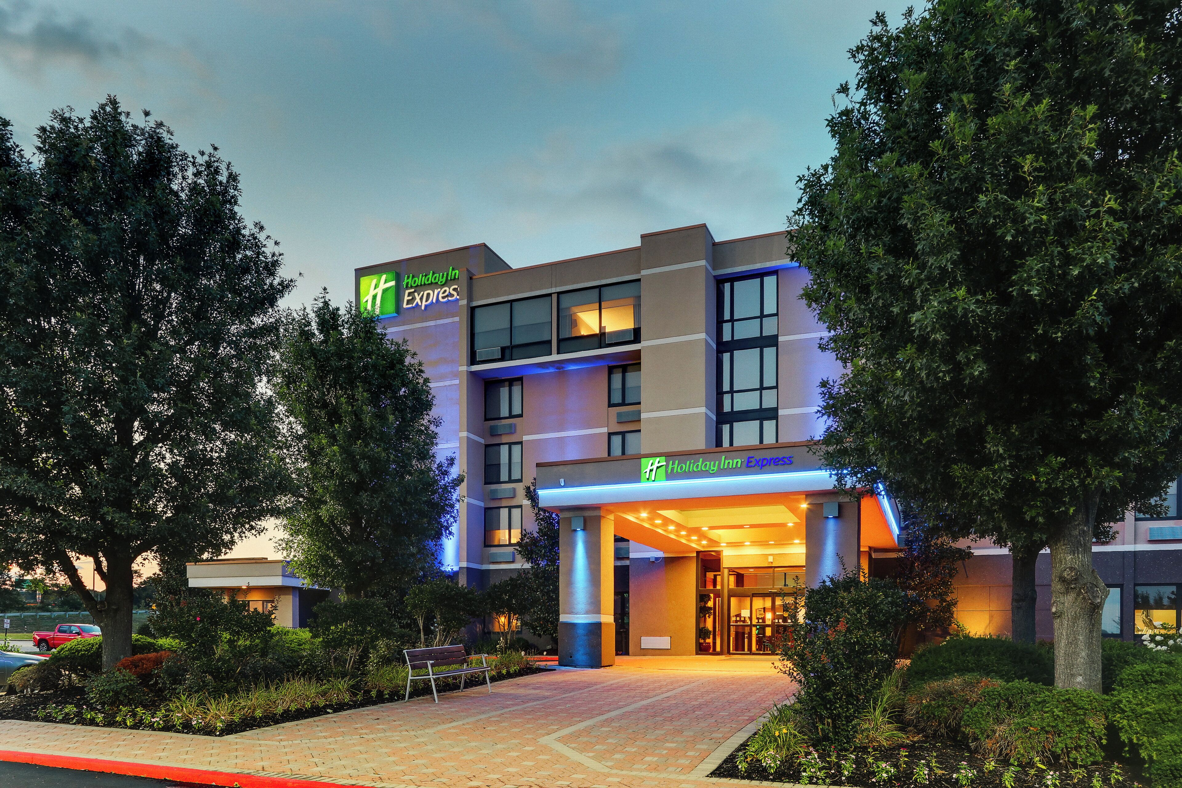 A Holiday Inn Express hotel with a modern design, featuring a prominent entrance and a landscaped outdoor area.