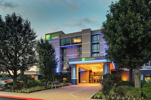 A Holiday Inn Express hotel with a modern design, featuring a prominent entrance and a landscaped outdoor area.
