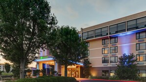 A hotel entrance with a modern design, large windows, and a well-maintained lawn.
