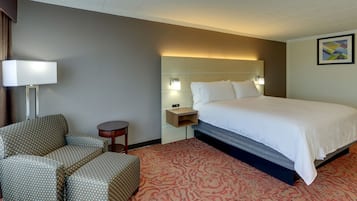 A hotel room with a bed, a sofa, a small table, and a lamp.