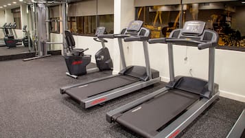 A gym with treadmills, weight machines, and a mirrored wall.
