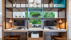 A modern office space with two desks, each with a computer, keyboard, and mouse. There are two chairs, a printer, and a typewriter on a shelf. - Holiday Inn Panama City by IHG (Panama City)