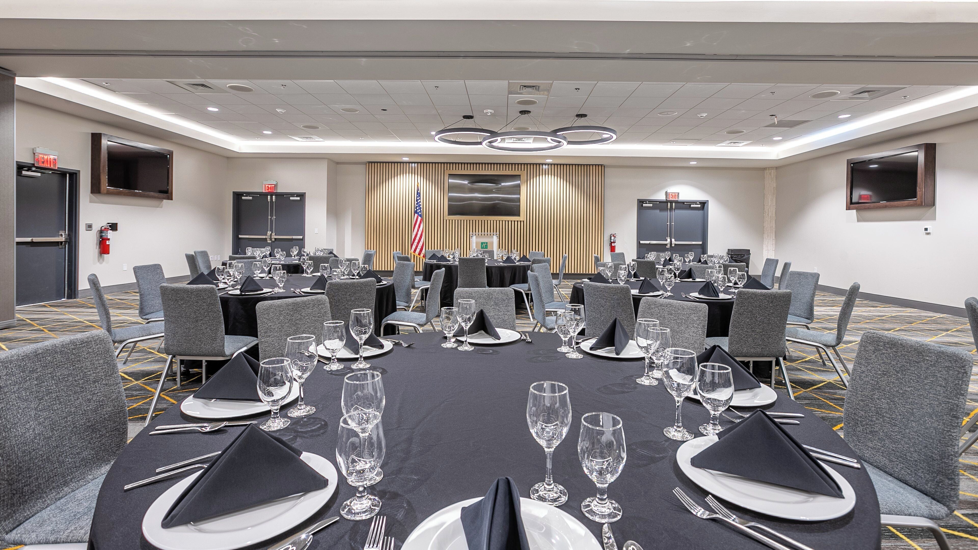 A conference room with tables set for dining, equipped with chairs, and a flag.