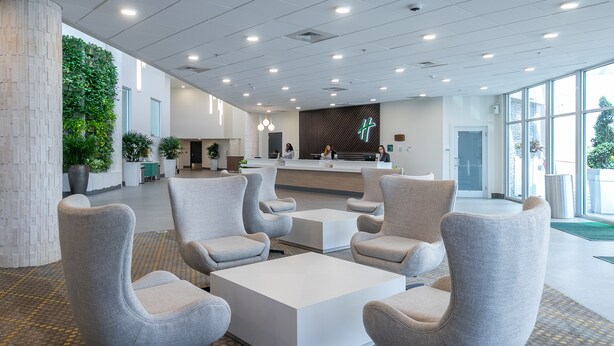 A modern lobby with a reception desk, seating area, and a green wall with plants. - Holiday Inn Panama City by IHG (Panama City)