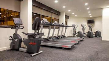 Een rij Life Fitness loopbanden in een sportschool met een vloerbedekking en grote ramen.