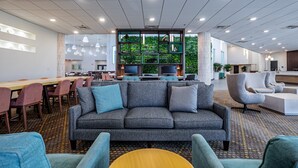 A modern lounge area with a grey sofa, blue armchairs, and a long wooden table. - Holiday Inn Panama City by IHG (Panama City)