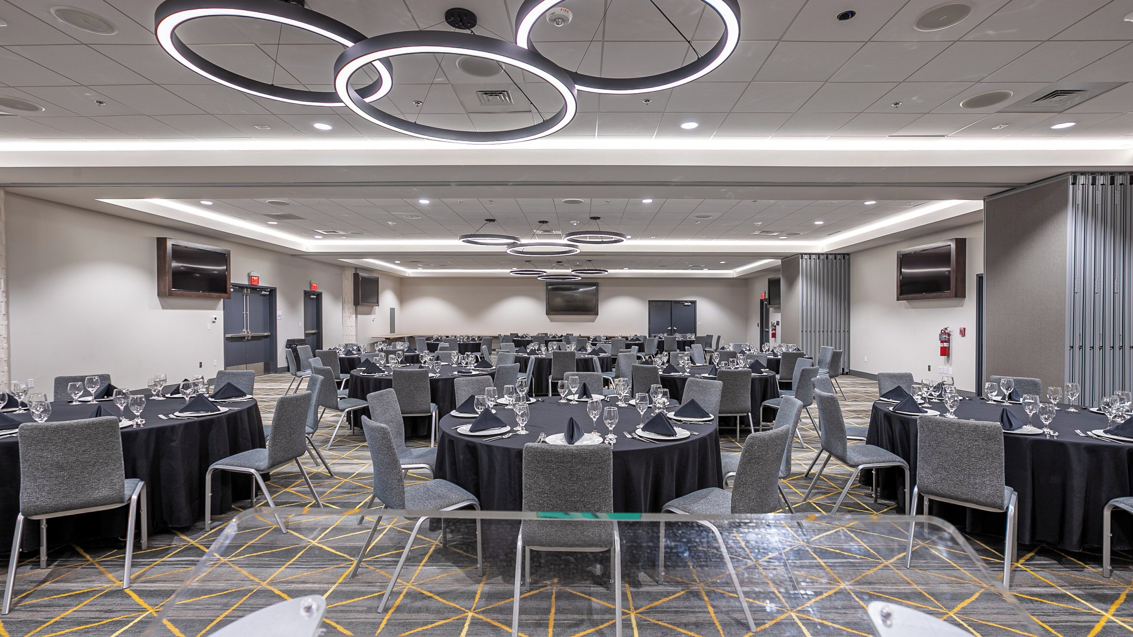 A conference room with round tables, chairs, and a patterned carpet.