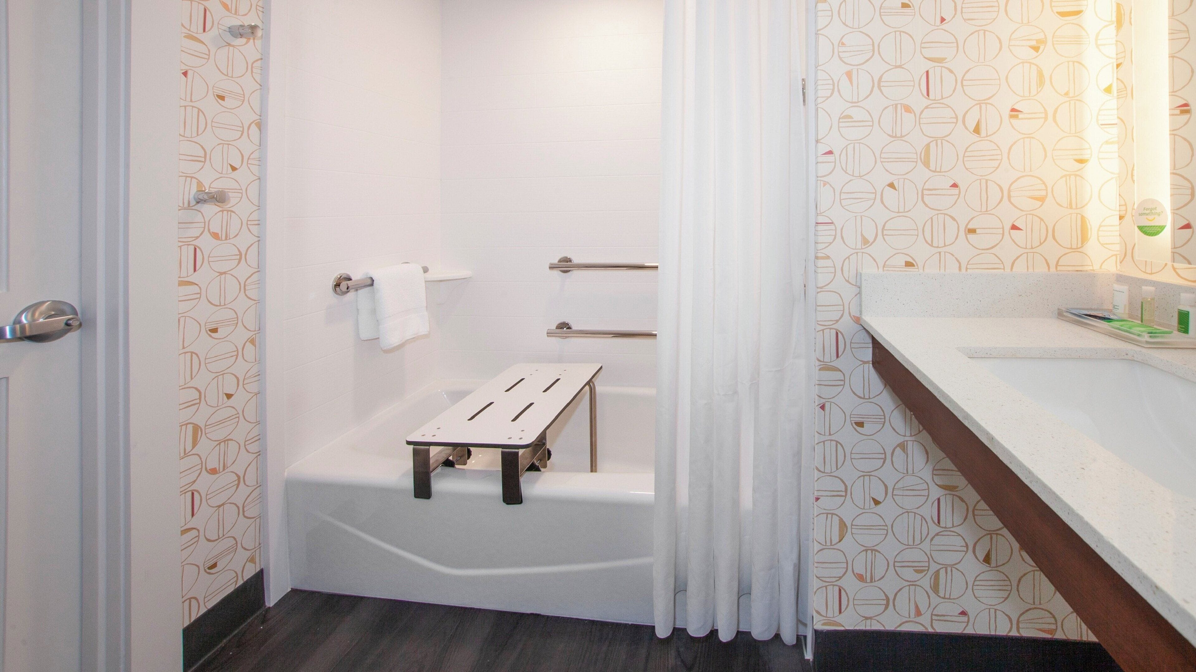 A bathroom with a bathtub, a shower, a vanity with a mirror, and a towel rack.