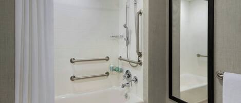 Et moderne badeværelse med badekar, bruser og gelænder.