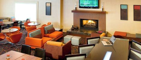 A hotel lobby with a fireplace, seating area, and a bar.