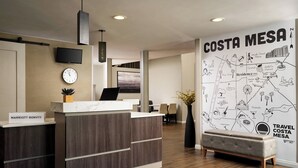 A hotel reception area with a map of Costa Mesa, a clock, and a sign for Marriott Bonvoy. - Residence Inn by Marriott Costa Mesa Newport Beach (Costa Mesa)
