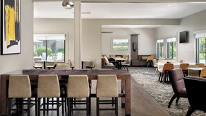 A spacious dining area with multiple tables and chairs, large windows offering views of the outdoors, and a modern interior design. - Residence Inn by Marriott Costa Mesa Newport Beach (Costa Mesa)
