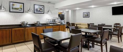 Un comedor moderno con armarios de madera, una barra de buffet y un televisor en la pared.