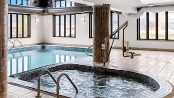 A modern indoor pool with a hot tub, large windows, and a tiled floor.