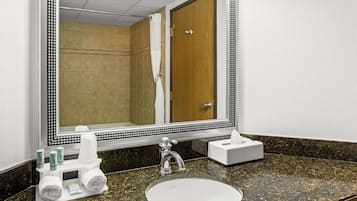 A bathroom with a large mirror, a sink, and a towel rack.