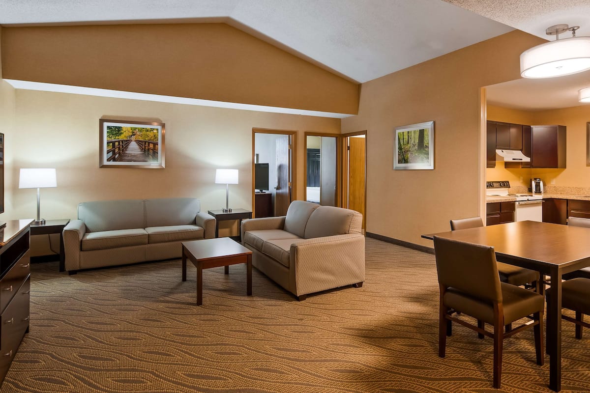 A hotel room with a living area, a dining table, and a kitchenette.