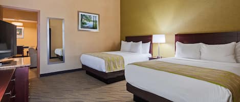 A hotel room with two beds, a large mirror, a desk, and a television.