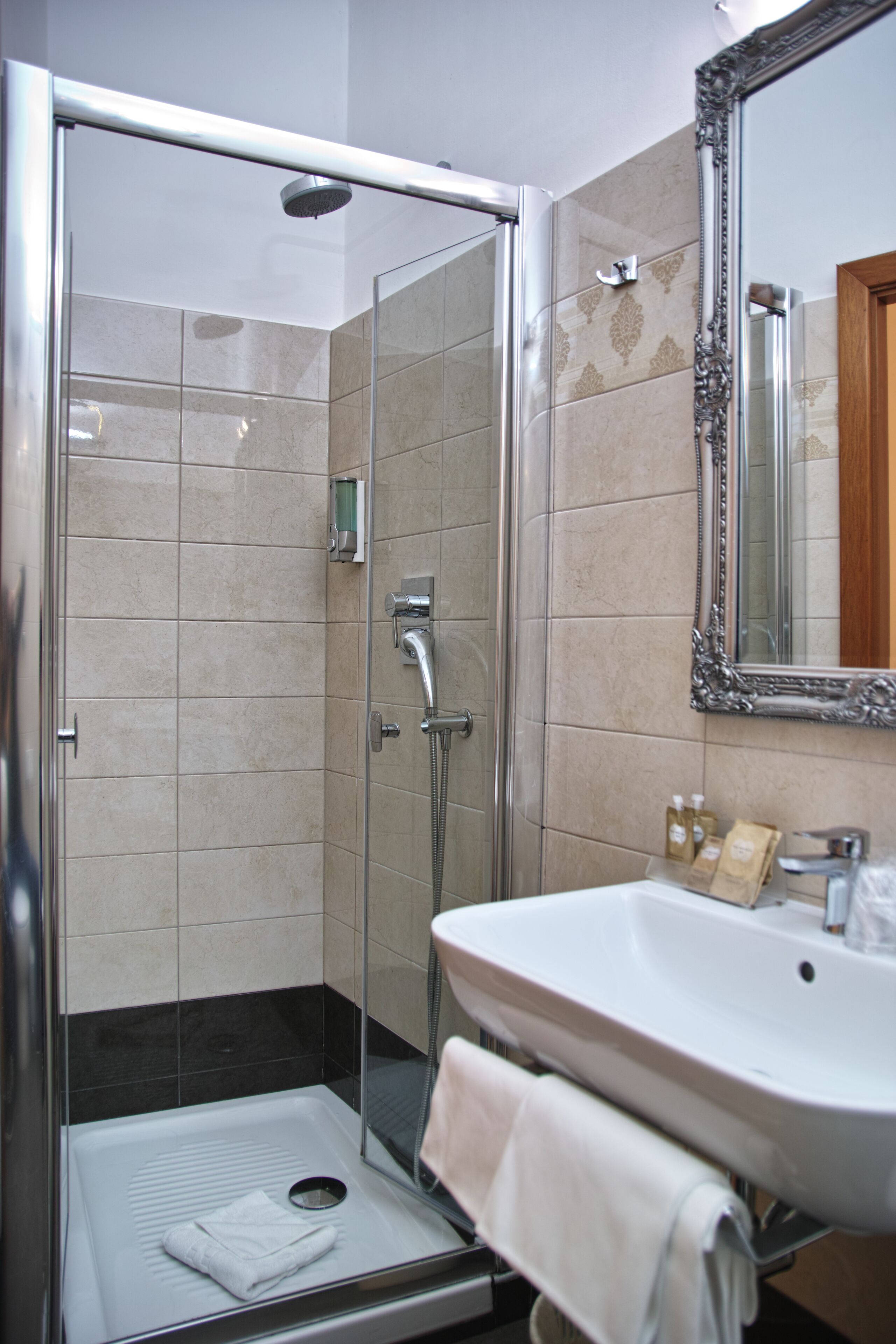 A modern bathroom with a glass-enclosed shower, a white sink, and a large mirror.