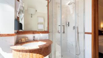Un bagno moderno con un lavabo in marmo, una cabina doccia in vetro e un mobile bagno in legno.