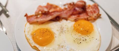 A breakfast setting with a plate of eggs and bacon, a glass of orange juice, and a cup of coffee on a table.