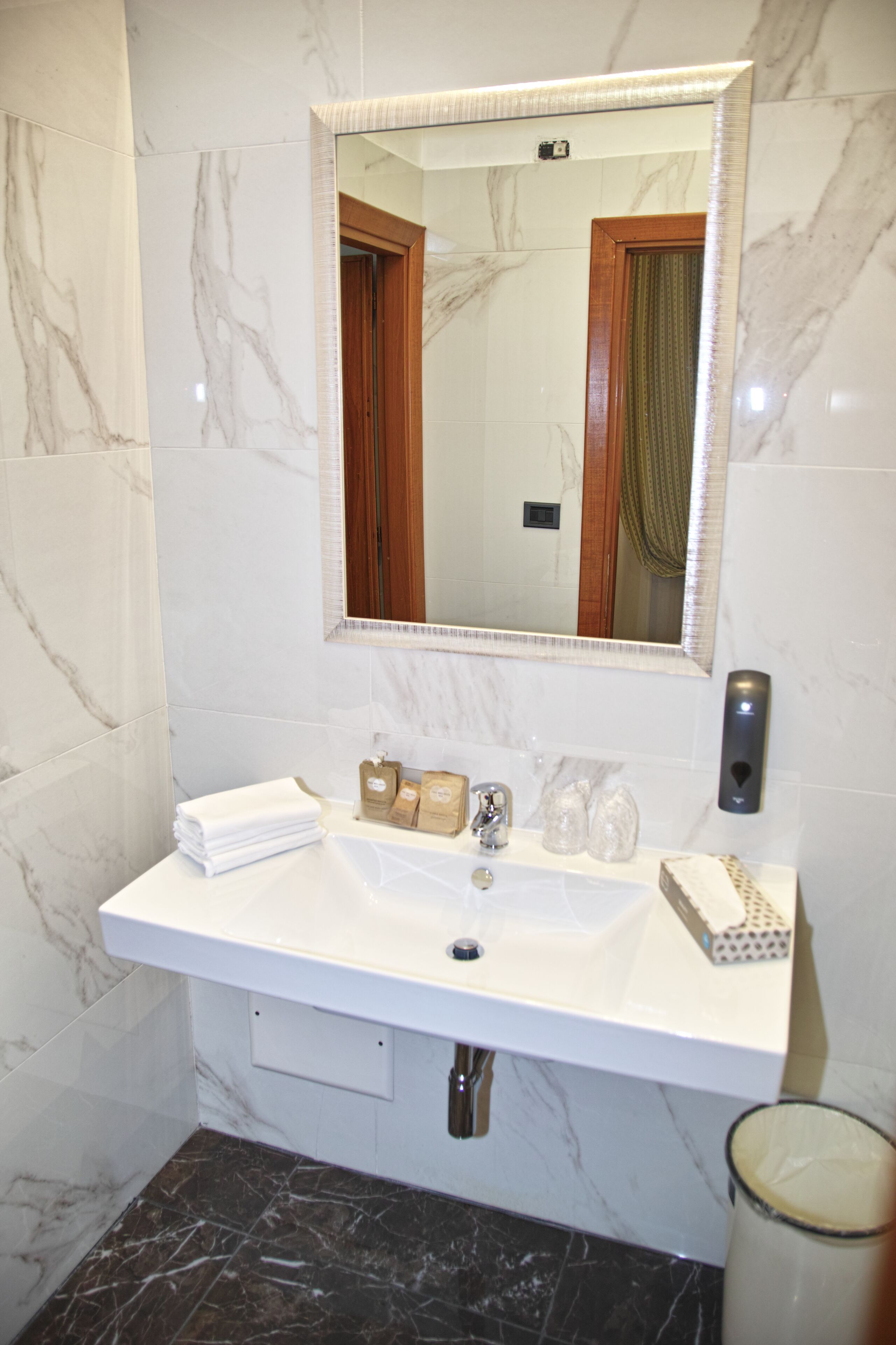 A bathroom with a white marble sink, a mirror, and a towel rack.