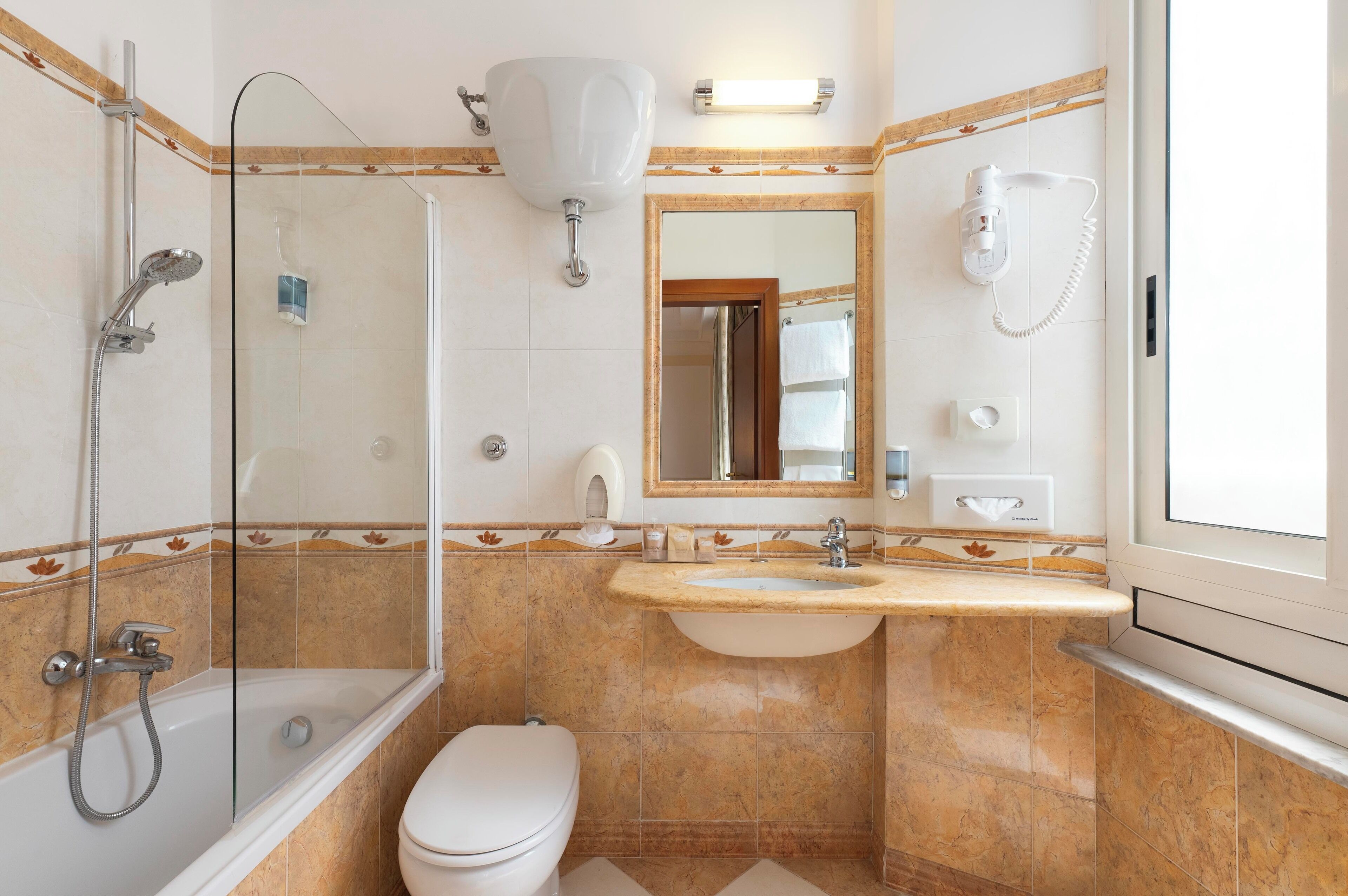 A bathroom with a glass-enclosed shower, a sink with a mirror above it, and a toilet.