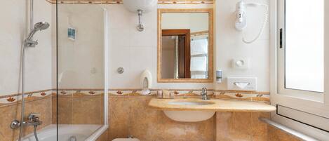 A bathroom with a glass-enclosed shower, a sink with a mirror above it, and a toilet.