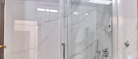 A modern bathroom with a glass-enclosed shower, a white toilet, and a marble-tiled floor.