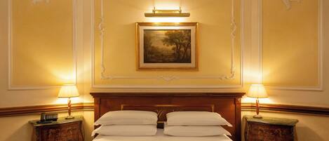 Una camera d'albergo con un letto grande, due comodini con lampade, un quadro incorniciato a parete e pannelli decorativi.