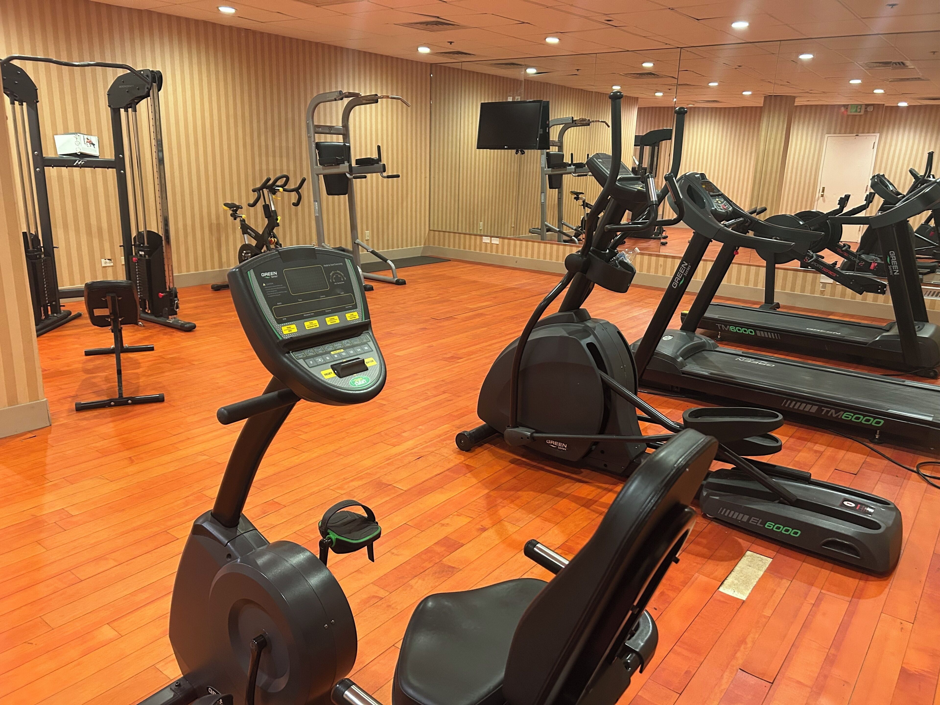 Un gimnasio con diferentes equipos de ejercicio, incluyendo cintas de correr, elípticas y máquinas de pesas.