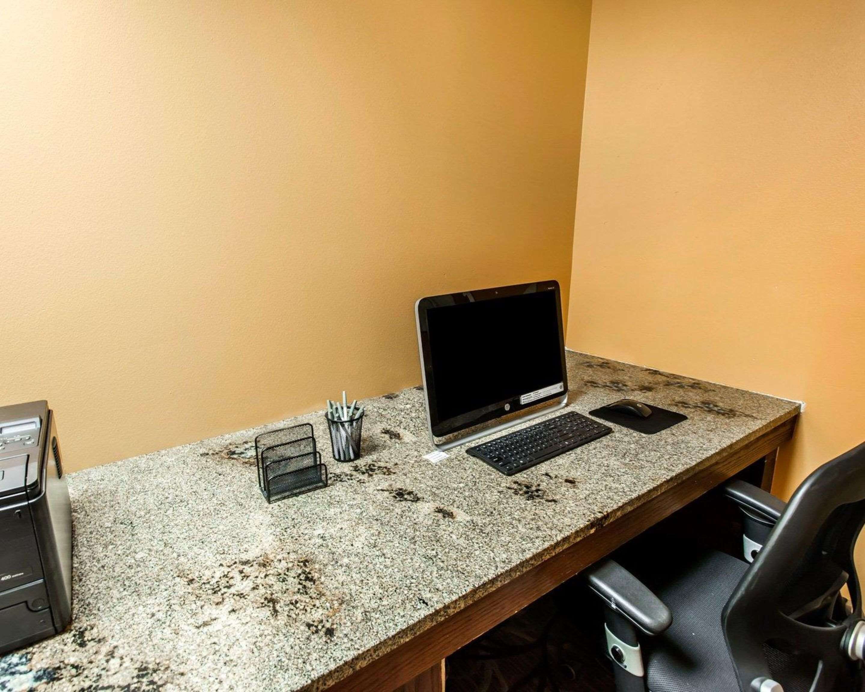 Et arbejdsområde med en stationær computer, tastatur, mus og en printer på et skrivebord i granit.