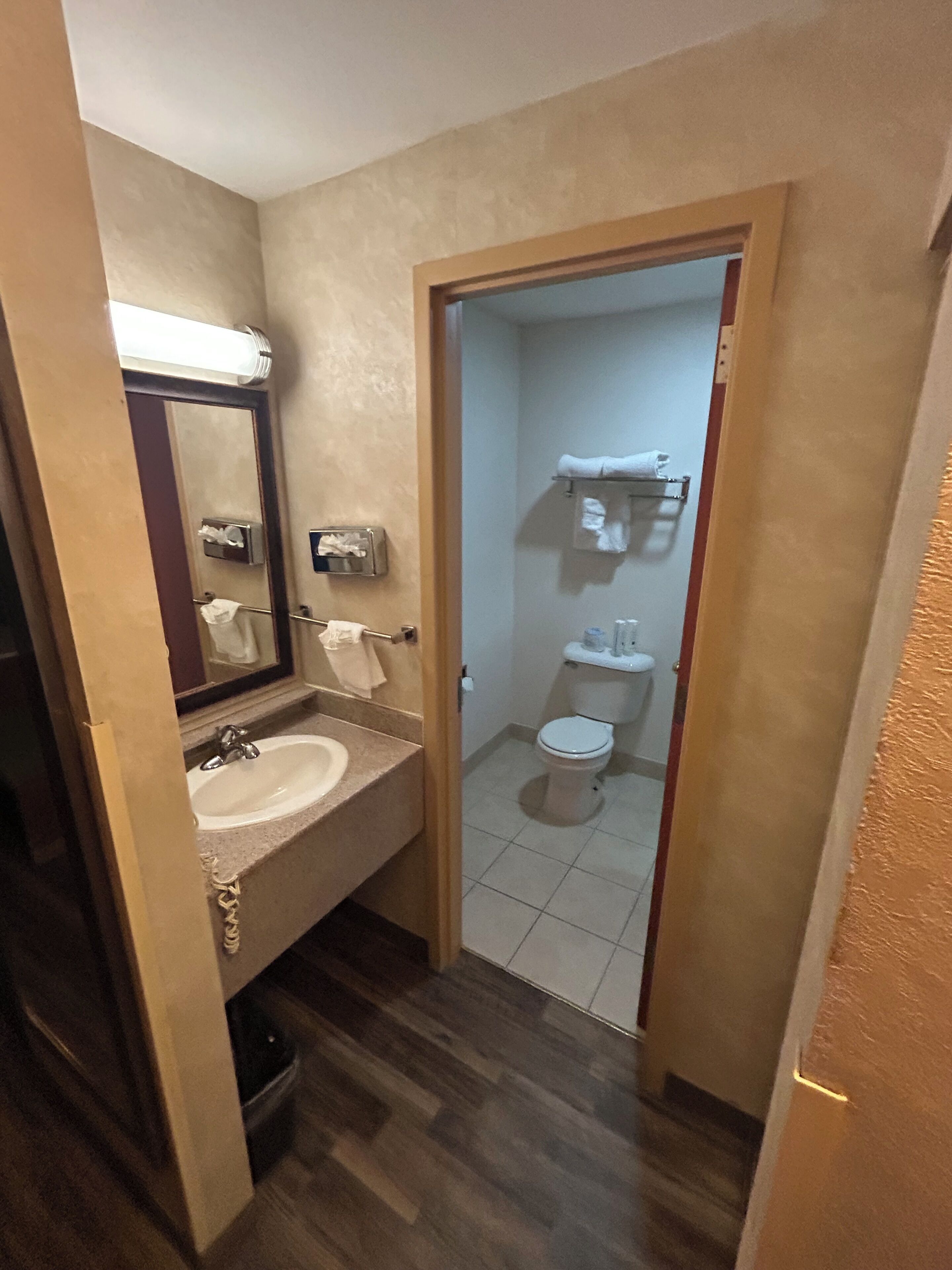 A bathroom with a sink, mirror, towel rack, and toilet.