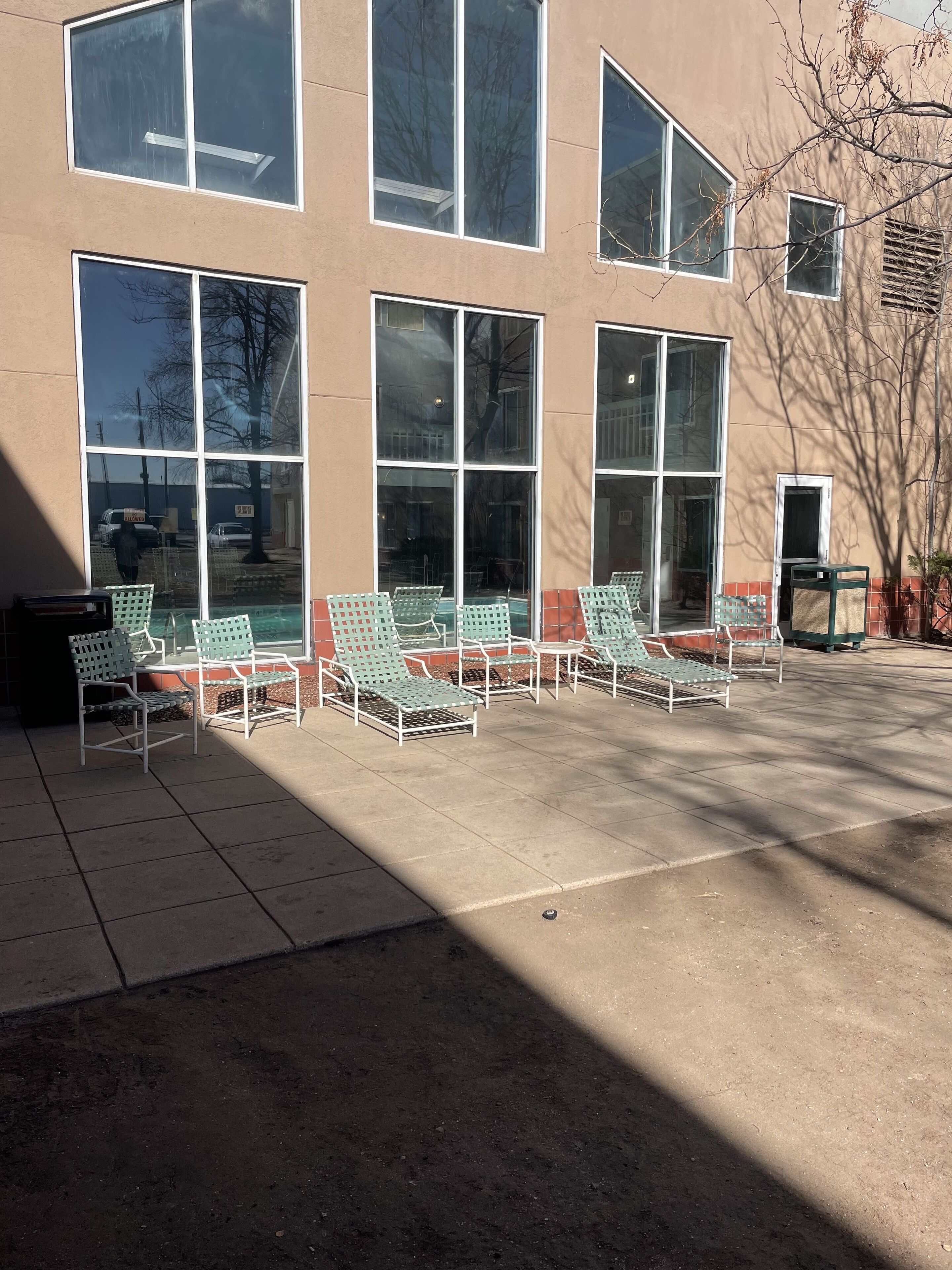 A building with large windows and outdoor seating with metal chairs.