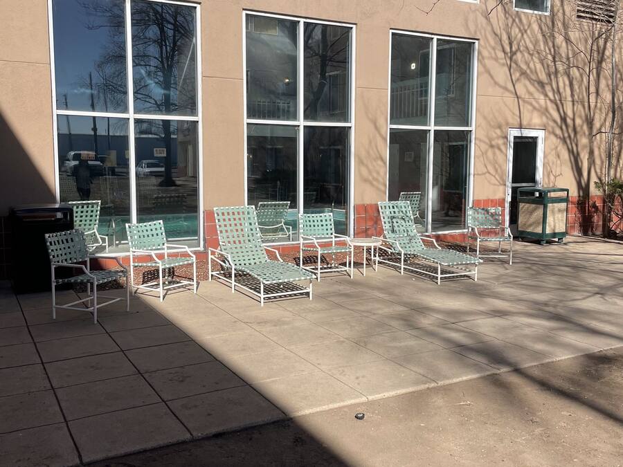 A building with large windows and outdoor seating with metal chairs.