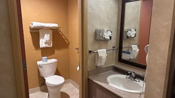 A hotel bathroom with a toilet, a sink, and a mirror.