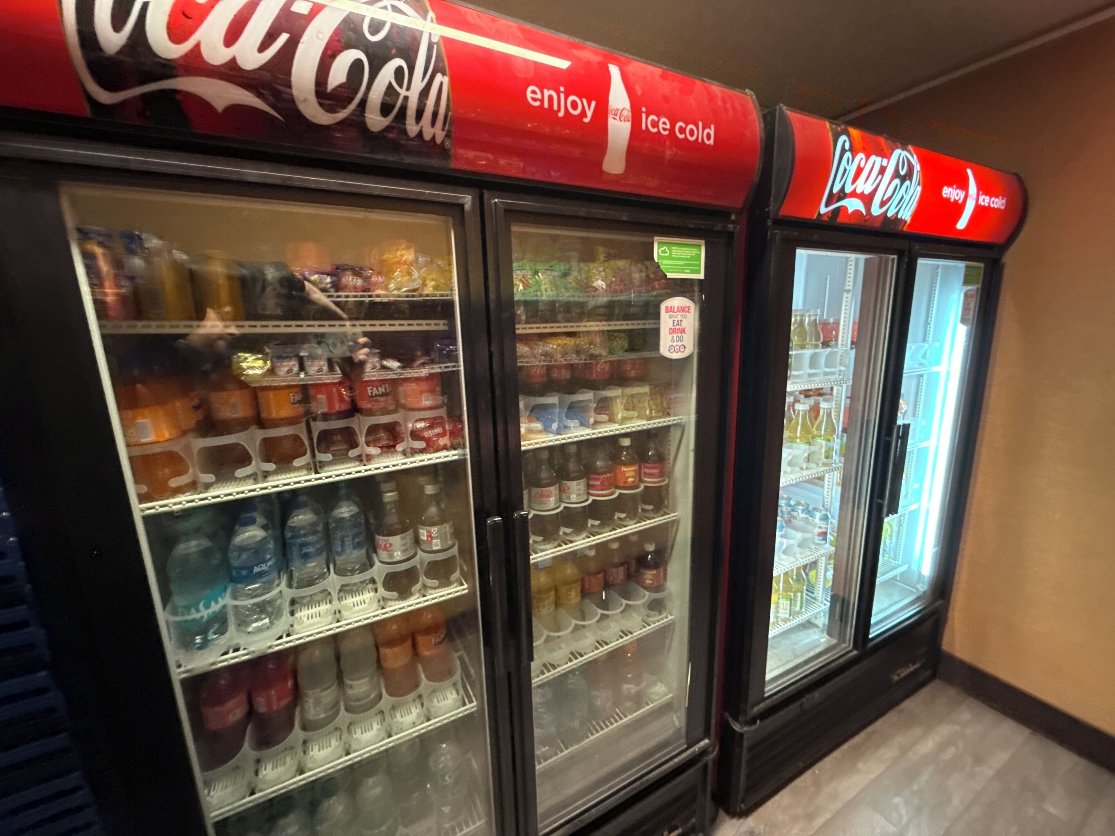 Tres máquinas expendedoras de Coca-Cola repletas de diversas bebidas.