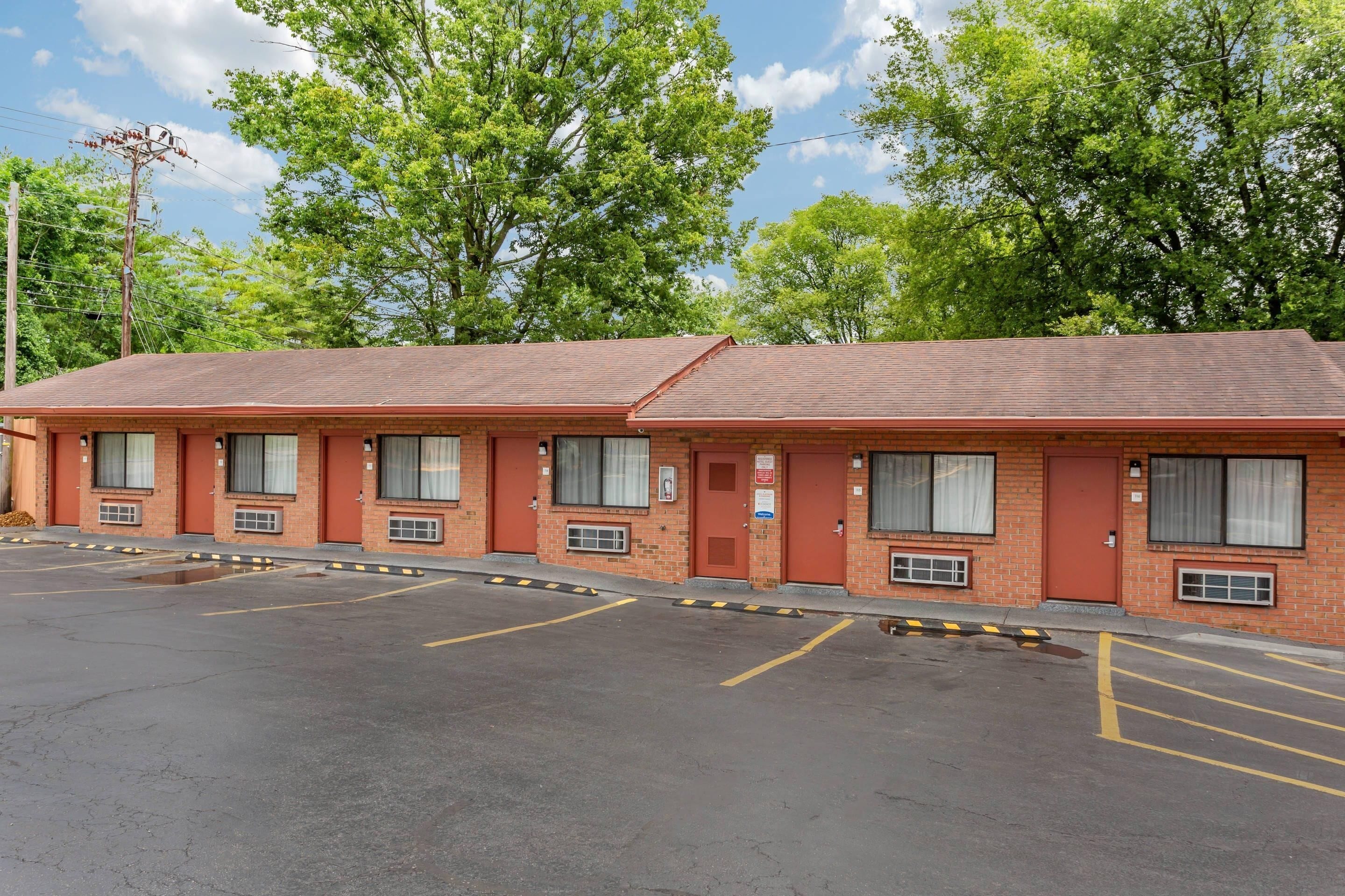 A motel with a brick facade, multiple windows, and a parking lot.