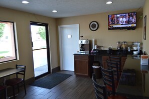 A small, well-lit kitchen with a coffee machine, a TV mounted on the wall, and a door leading outside. - Econo Lodge Nashville North (Nashville)