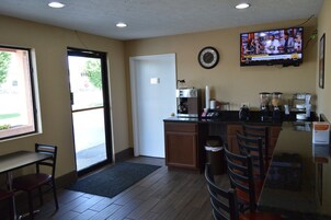 Una cocina pequeña y luminosa con una cafetera, un televisor montado en la pared y una puerta que da al exterior.