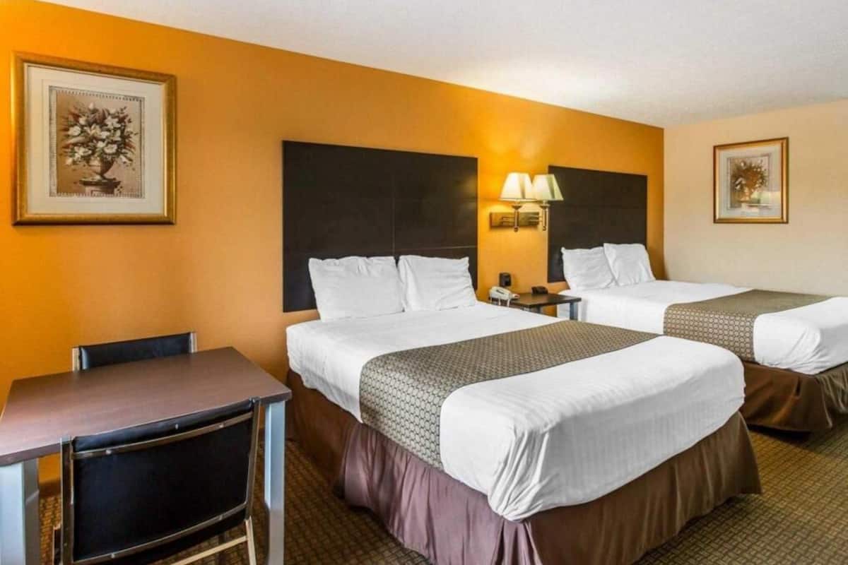 Ein Hotelzimmer mit zwei Betten, einem Schreibtisch und einem Stuhl.