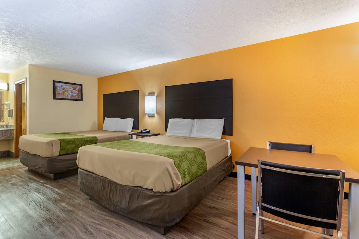 Ein Hotelzimmer mit zwei Betten, einem Schreibtisch und einem Stuhl.