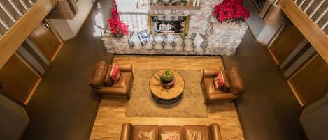 A spacious living area with a stone fireplace, leather sofas, and a wooden coffee table.