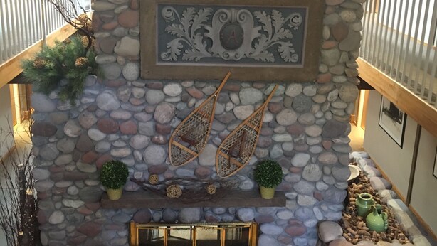 A stone fireplace with a decorative plaque, two hanging fans, and a small potted plant. - Aspen Mountain Lodge (Aspen)