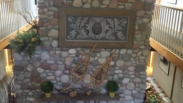 Lareira de pedra com uma placa decorativa, duas ventoinhas penduradas e um pequeno vaso com planta.