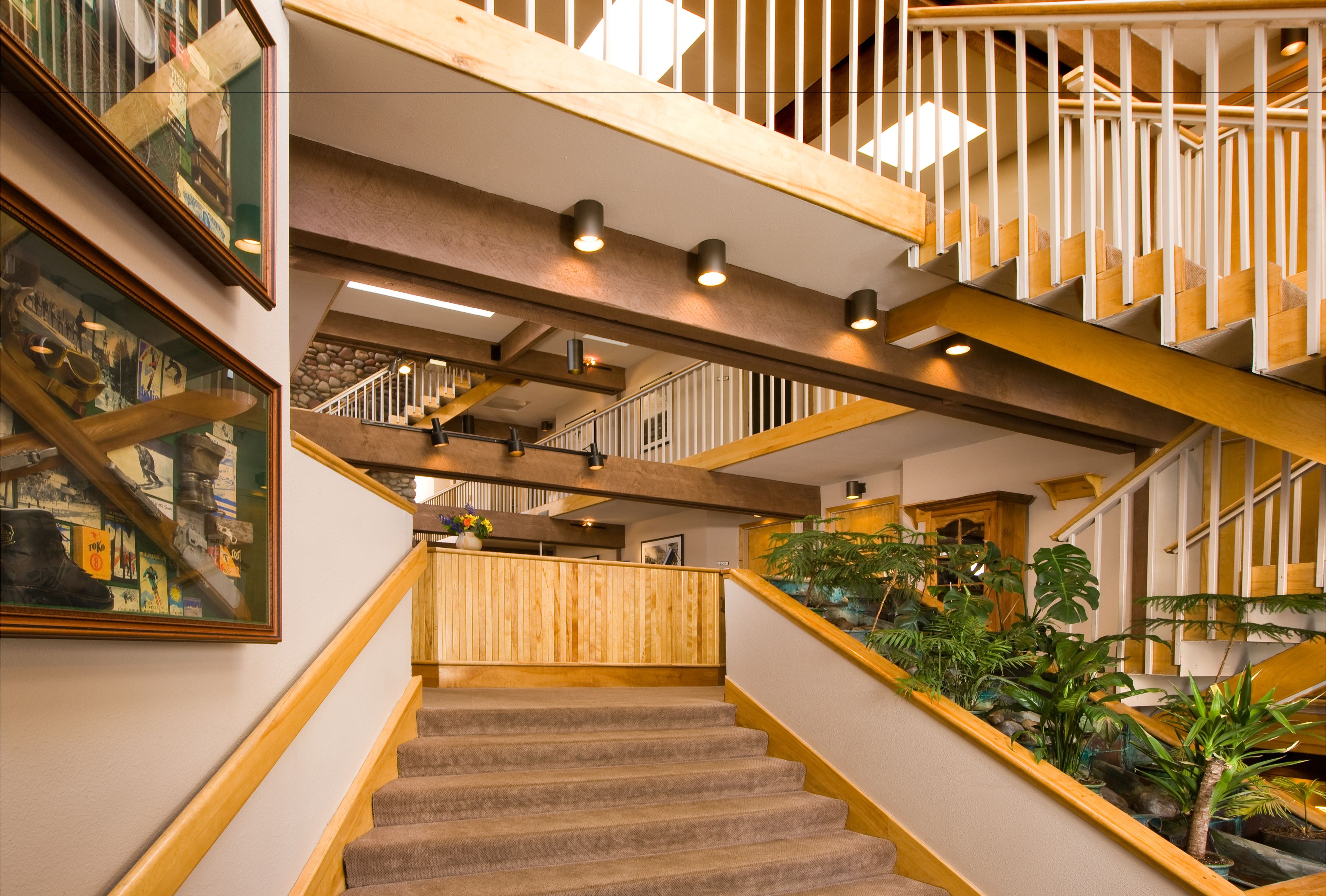 A staircase with wooden railings and carpeted steps, leading to a second floor with a railing and a view of the interior.